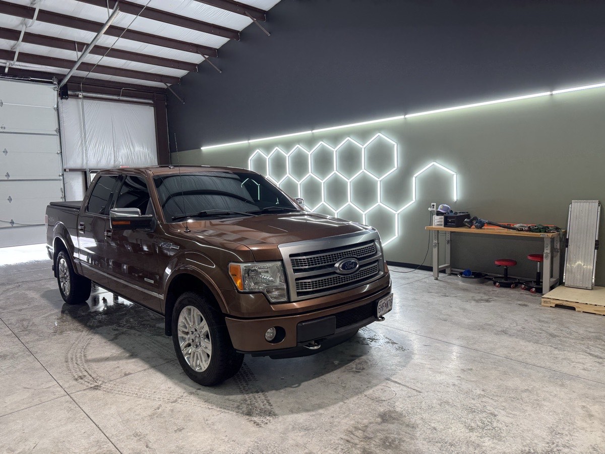 A pickup truck with newly installed window tint in a lit shop bay