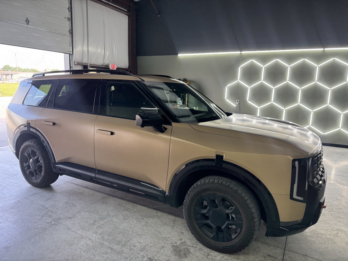 An SUV finished in a satin colour change wrap in a lit shop bay